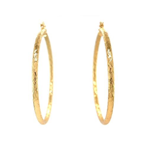 The Huge Zigzag Texturized Hoops Earrings, crafted in 14k gold-filled material, feature a bold zigzag pattern against a white background, creating a striking statement piece.